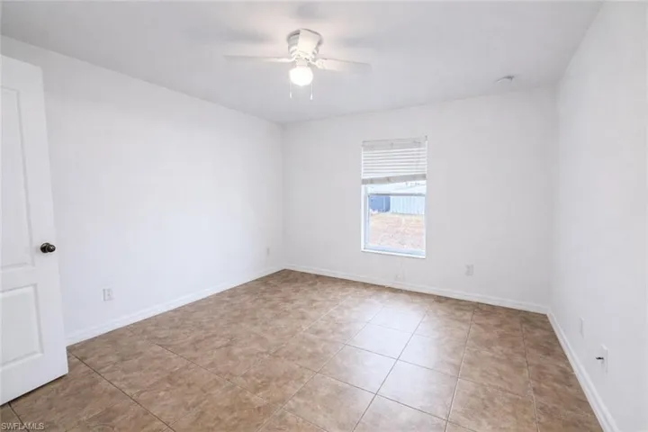 Empty room featuring a ceiling fan and light tile patterned flooring