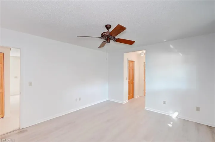 Unfurnished room with ceiling fan, a textured ceiling, and light wood-type flooring