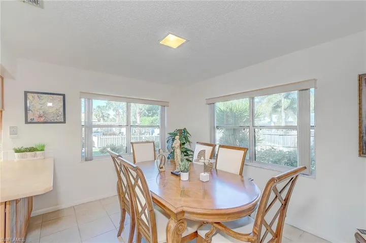 Dining space with light tile patterned flooring, a wealth of natural light, and a textured ceiling