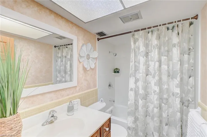 Full bathroom with vanity, tile walls, toilet, and shower / bath combo with shower curtain