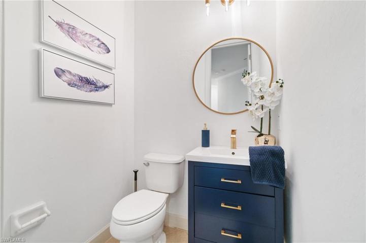 3rd bath is a guest powder wih designer navy cabinetry, brass lighting and fixtures.