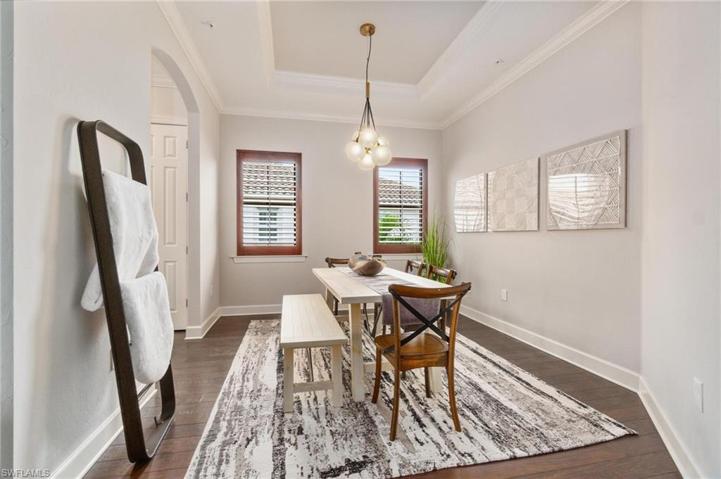 Spacious formal dining room features designer lighting and rich wood plantation shutters
