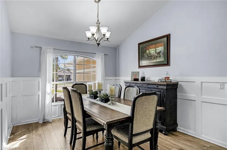 Dining area with a notable chandelier, vaulted ceiling, and light wood-type flooring