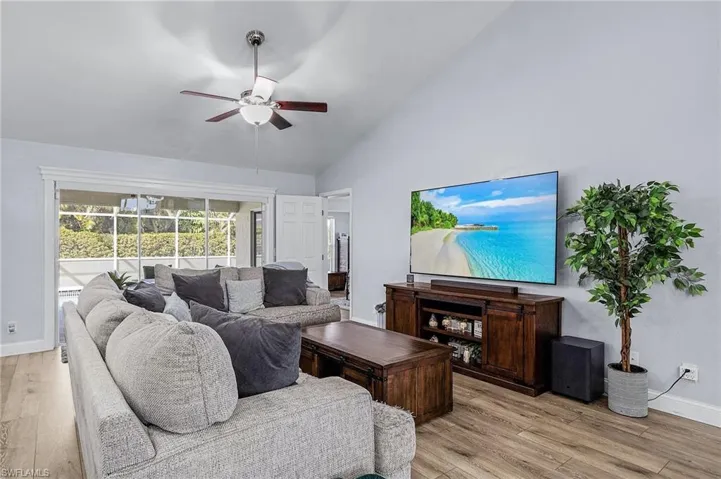 Living room with light hardwood / wood-style flooring, high vaulted ceiling, and ceiling fan
