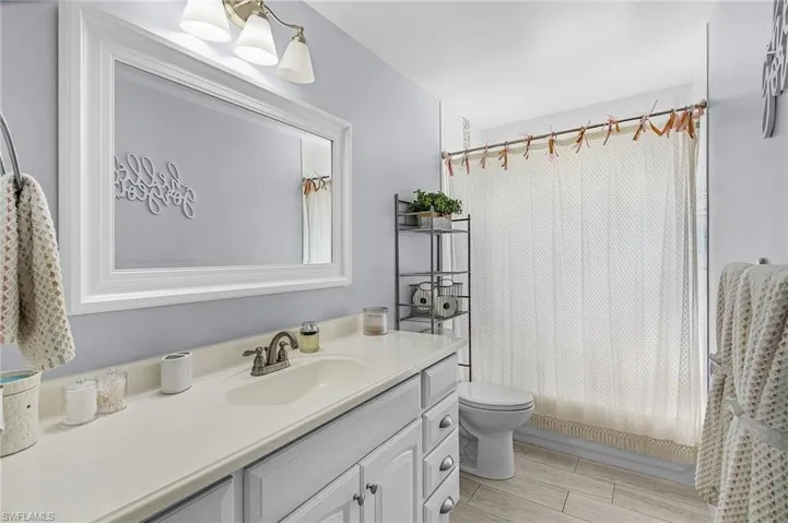 Full bathroom featuring vanity, shower / tub combo, wood-type flooring, and toilet