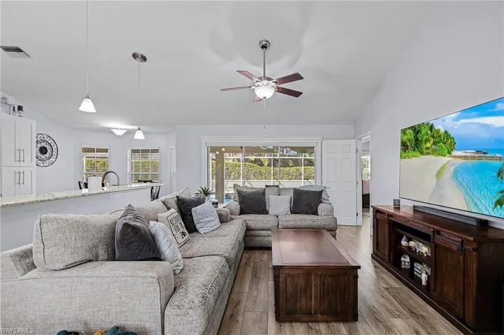 Living room with ceiling fan, lofted ceiling, sink, and light hardwood / wood-style flooring
