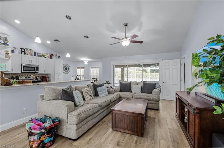 Living room featuring high vaulted ceiling, light hardwood / wood-style floors, and ceiling fan