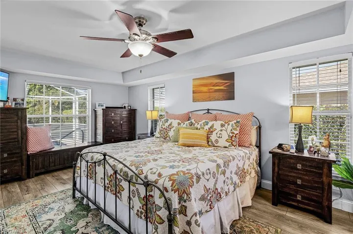 Bedroom with ceiling fan, multiple windows, and light hardwood / wood-style flooring
