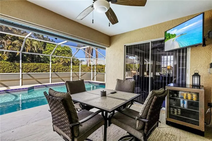 View of patio with a fenced in pool, ceiling fan, and glass enclosure