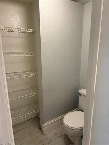 Powder room featuring a standard white toilet and wood-finish flooring