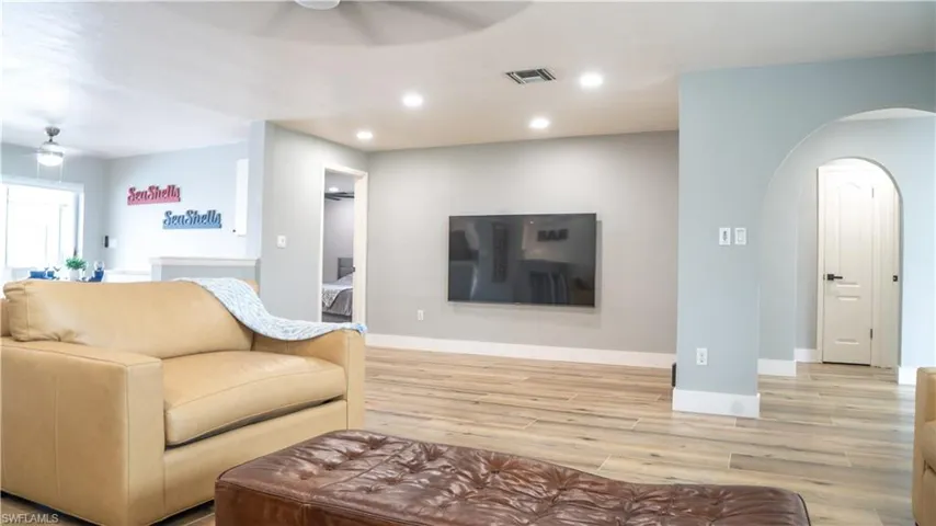 Spacious living area featuring wood-finish flooring, recessed lighting, and an arched doorway