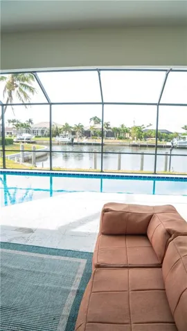 Screened outdoor living area featuring a pool, canal frontage, and a concrete patio