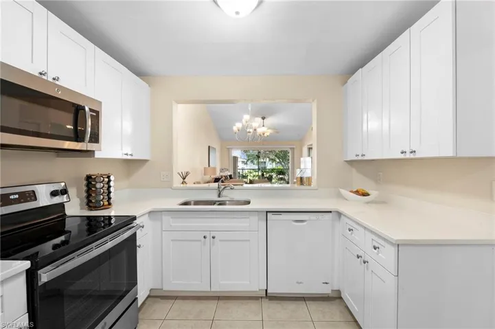 Kitchen with white cabinetry, a chandelier, stainless steel appliances, and sink