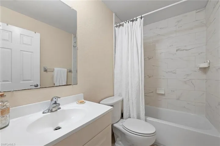 Full bathroom featuring vanity, toilet, and shower / bathtub combination with curtain