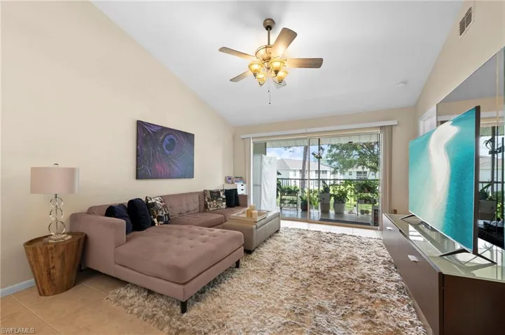 Living room featuring lofted ceiling, ceiling fan, and light tile patterned flooring