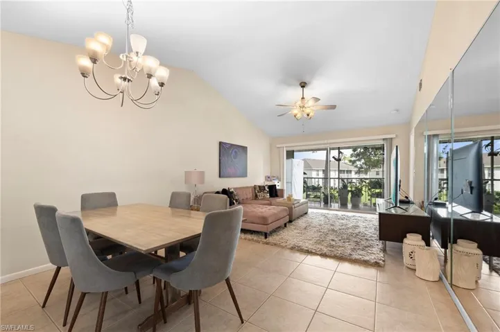 Tiled dining area featuring ceiling fan with notable chandelier and vaulted ceiling