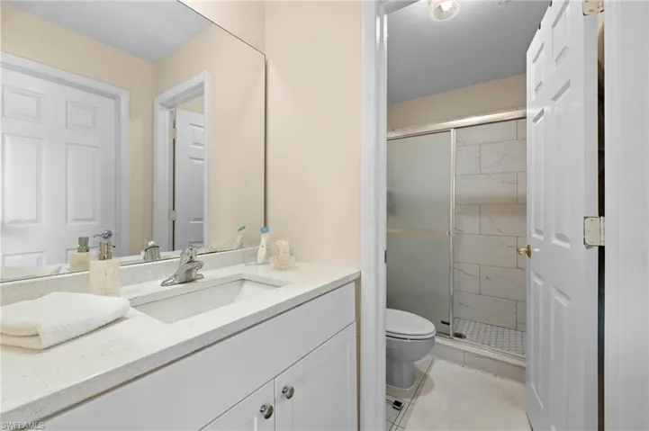 Bathroom with vanity, toilet, tile patterned flooring, and a shower with door