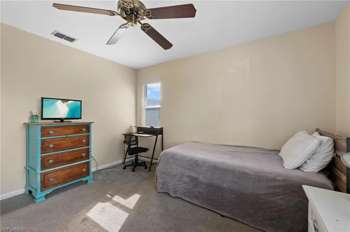 Bedroom with ceiling fan and light colored carpet