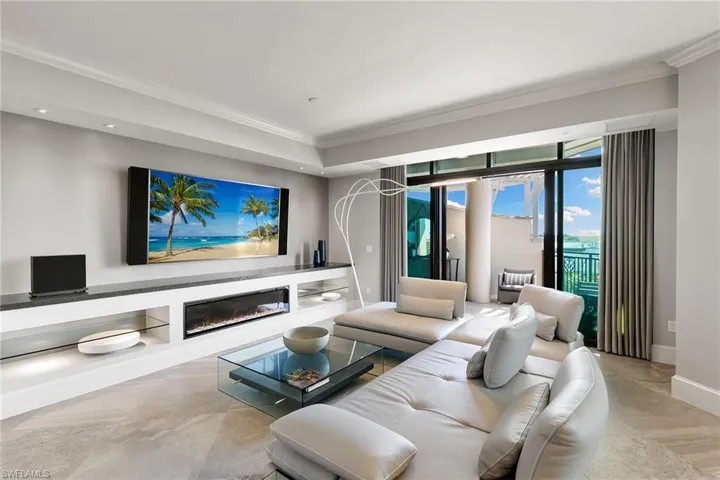 Living area with a glass covered fireplace, crown molding, and recessed lighting