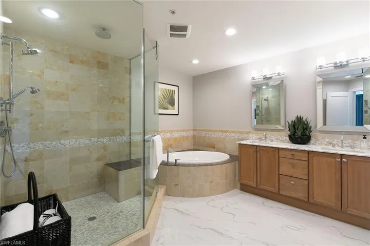 Full bath with double vanity, a garden tub, a stall shower, and recessed lighting