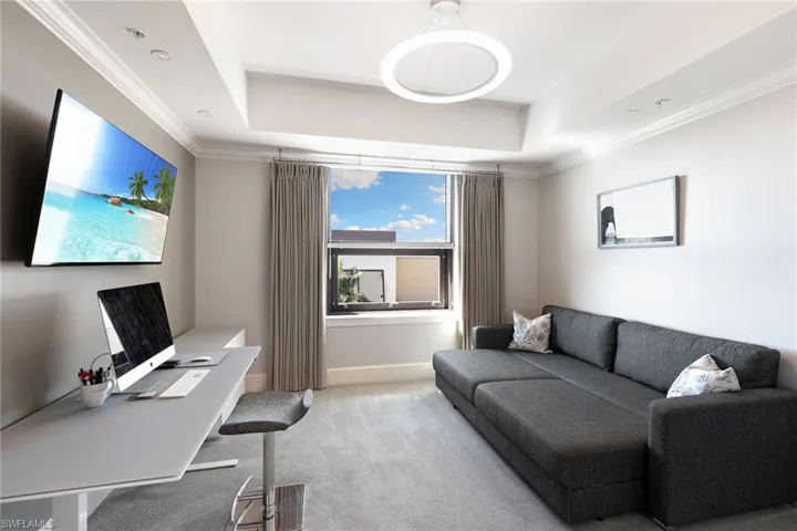 Office with ornamental molding, carpet flooring, and a tray ceiling