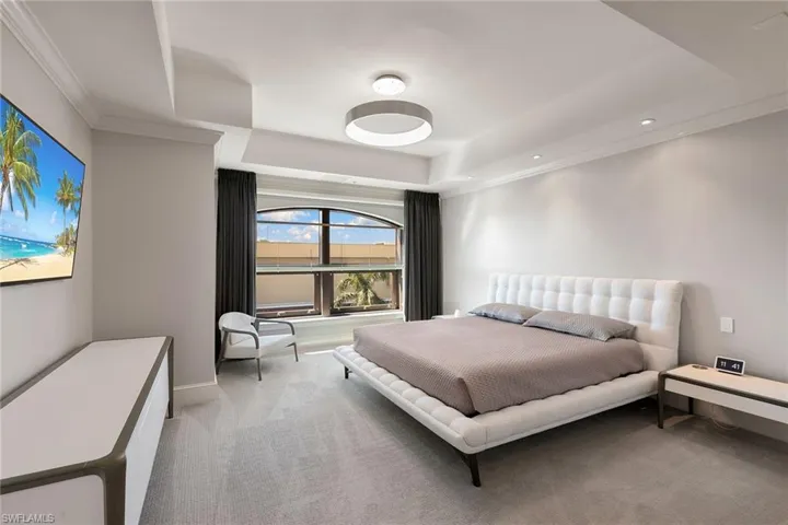 Bedroom featuring light carpet, a raised ceiling, and ornamental molding