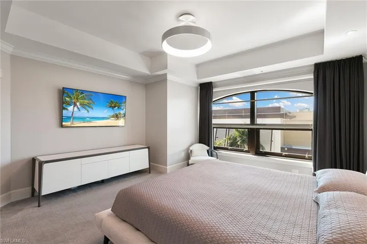Carpeted bedroom featuring a raised ceiling and ornamental molding