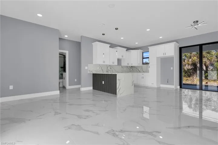 Kitchen with white cabinets, open floor plan, light stone countertops, recessed lighting, and a peninsula