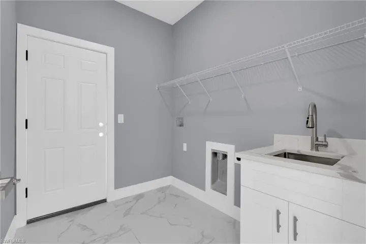 Laundry room with light marble finish flooring, washer hookup, and cabinet space
