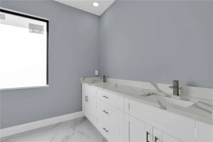 Full bathroom with double vanity, light marble finish floors, and recessed lighting