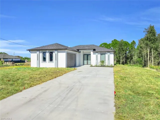 Prairie-style home featuring stucco siding, concrete driveway, a front lawn, and a garage