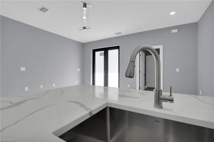 Kitchen featuring light stone counters, french doors, and recessed lighting