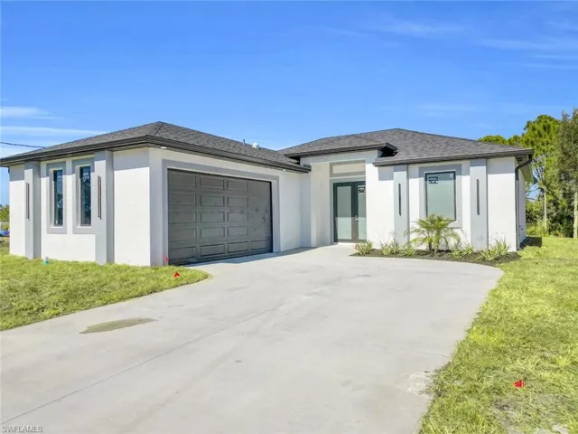 Prairie-style home featuring stucco siding, driveway, a front lawn, and a garage