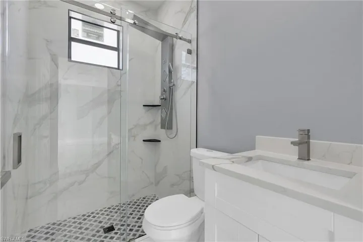 Bathroom featuring vanity and a marble finish shower