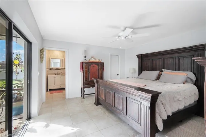 Bedroom featuring a ceiling fan, light tile patterned floors, and ensuite bathroom