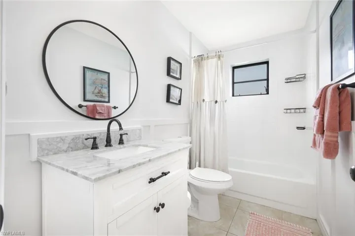 Full bath featuring vanity, shower / bath combo, and light tile patterned flooring