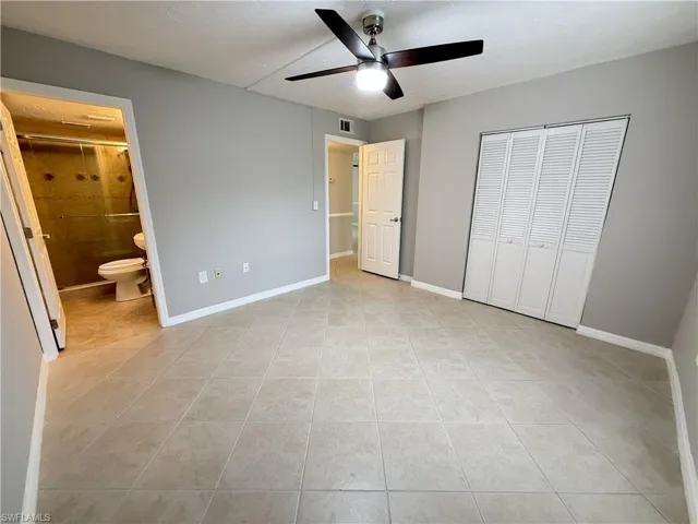 Unfurnished bedroom featuring a closet, ceiling fan, light tile patterned floors, and connected bathroom