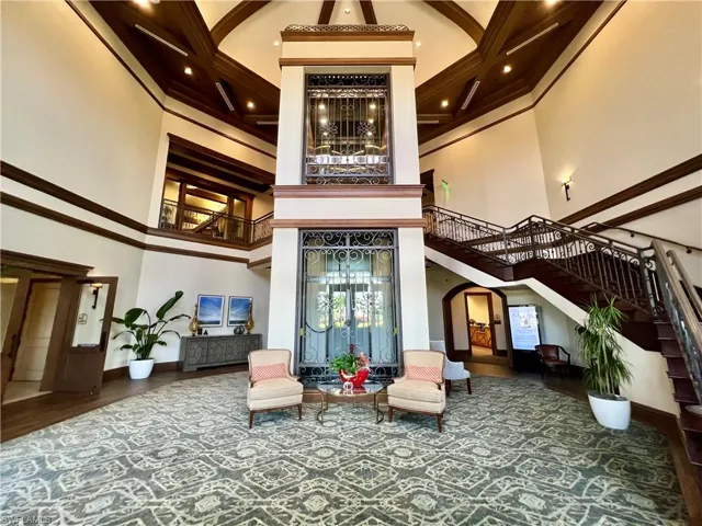 Building lobby with a high ceiling, stairway, ornamental molding, and beam ceiling