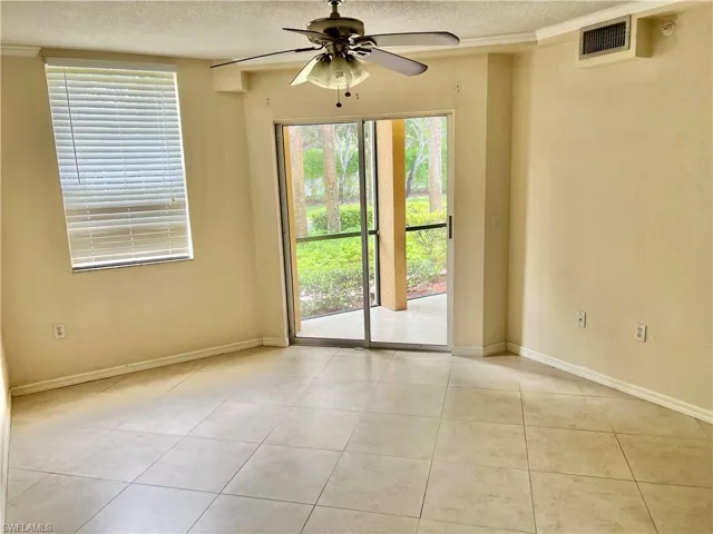Spacious room with light-toned tile flooring, a ceiling fan with light fixture, and a large sliding glass door opening to an outdoor patio