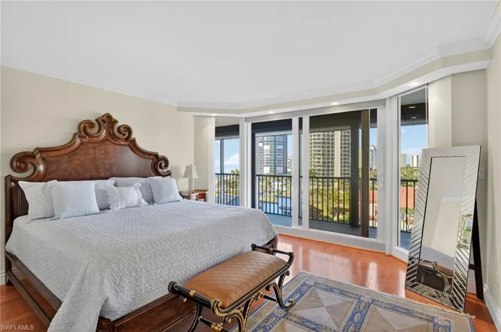 Bedroom with light wood finished floors, ornamental molding, multiple windows, expansive windows, and access to outside