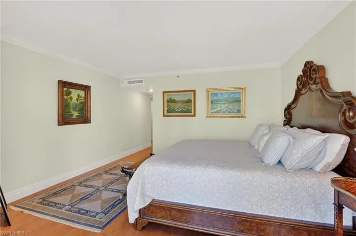 Bedroom with wood finished floors and crown molding