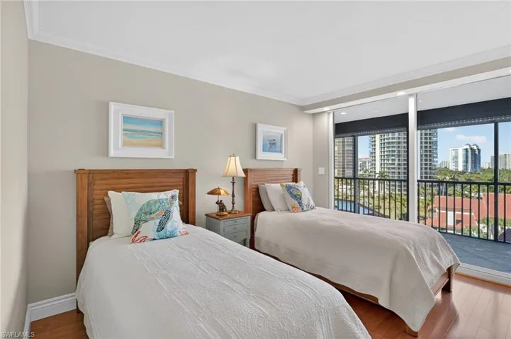Bedroom featuring crown molding, wood finished floors, access to outside, a city view, and floor to ceiling windows