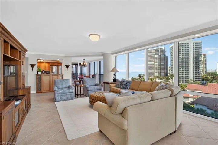 Living area featuring hanging lights, crown molding, light tile patterned floors, and a city view