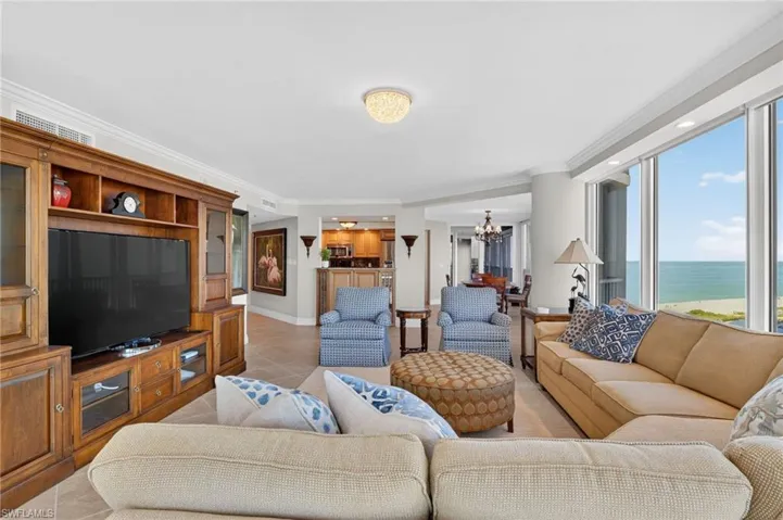 Living room with crown molding, a water view, hanging lights, and light tile patterned flooring