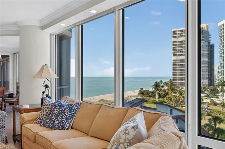 Living area featuring ornamental molding, view of water and beach, and recessed lighting