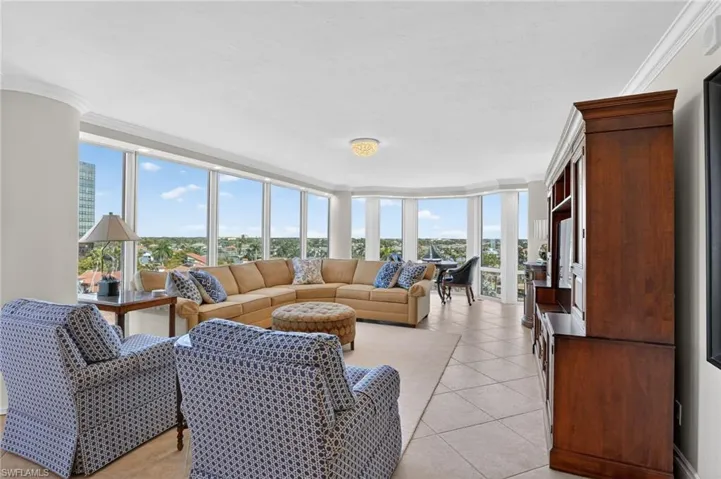 Living room featuring ornamental molding, healthy amount of natural light, light tile patterned flooring, and floor to ceiling windows