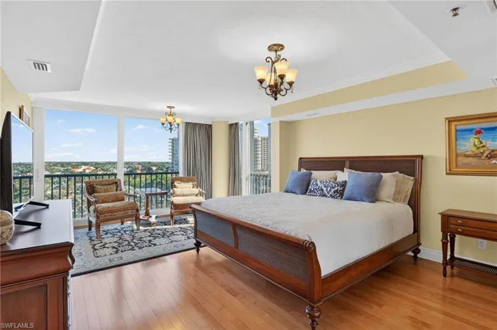 Bedroom featuring crown molding, light wood-style floors, hanging lights, access to outside, and expansive windows
