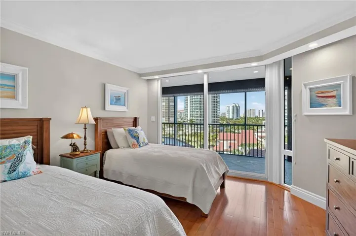 Bedroom with crown molding, light wood-style flooring, a skyline view, and access to exterior
