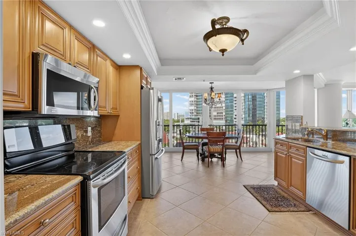 Kitchen featuring stainless steel appliances, dark stone countertops, tasteful backsplash, wood finish cabinets, and ornamental molding
