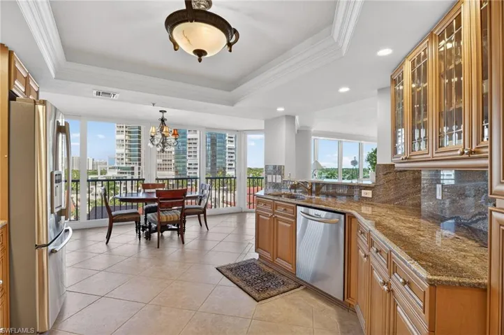 Kitchen with ornamental molding, glass fronted cabinets, wood finish cabinetry, stainless steel appliances, and dark stone counters